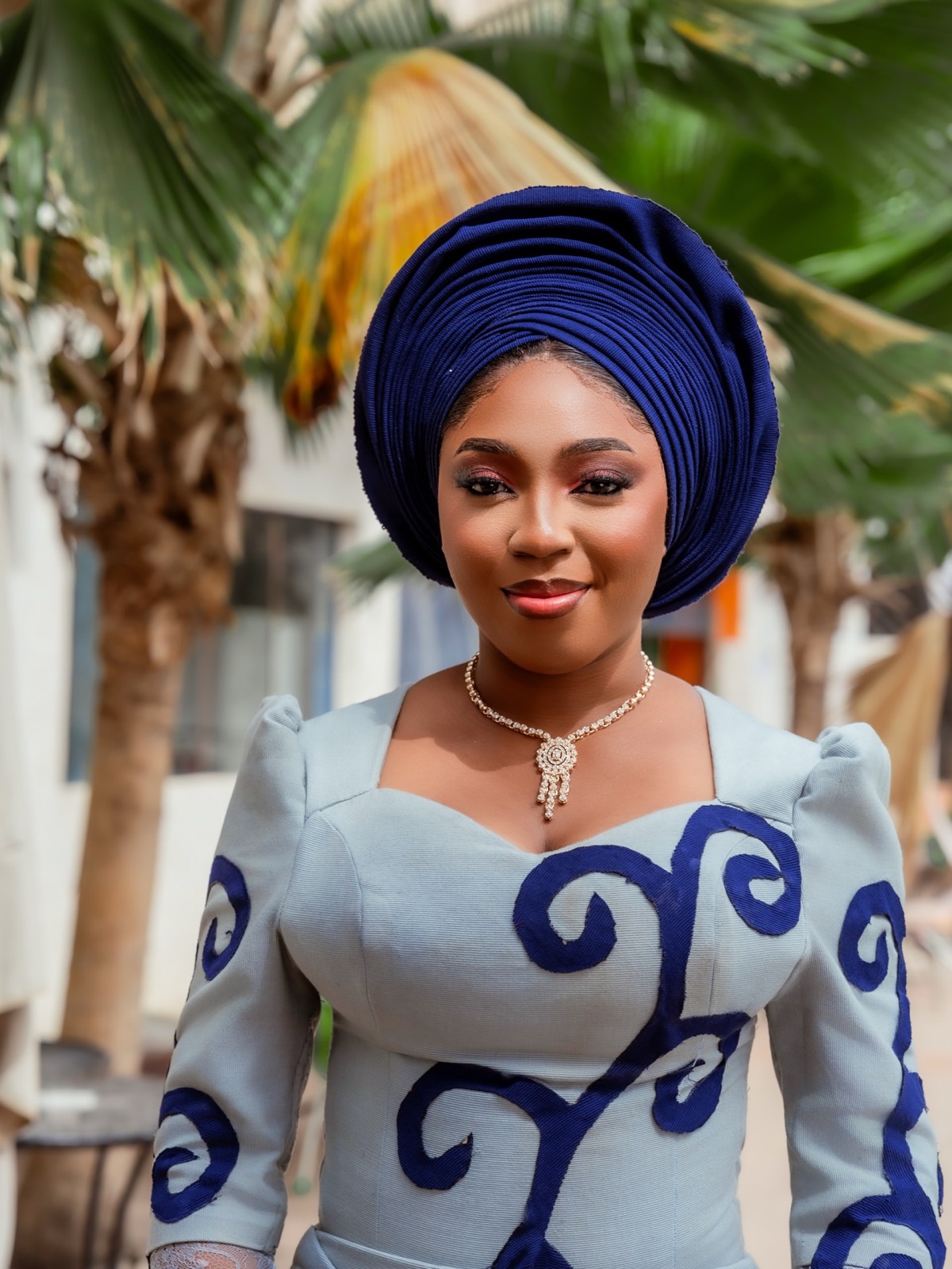 Woman in blue gele and patterned dress