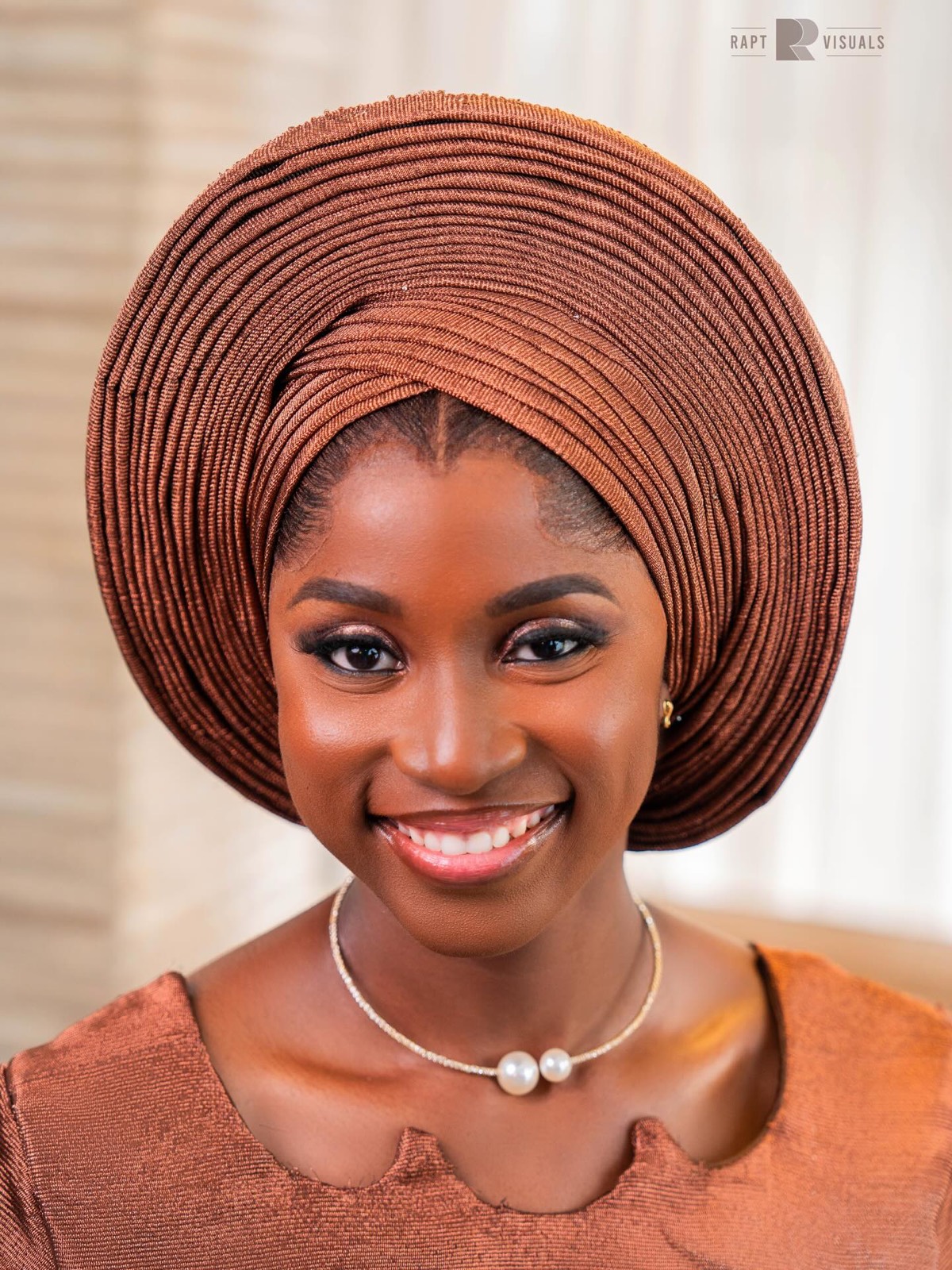Close portrait of a smiling woman in a copper gele